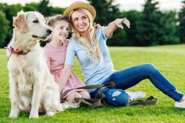 Parkta köpeği olan bir anne ve kız.