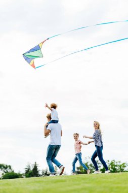 family playing with kite at park clipart