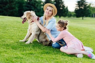 Parkta köpeği olan bir anne ve kız.