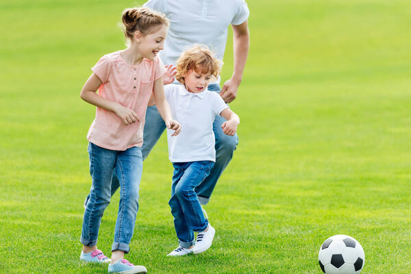 father with kids playing soccer