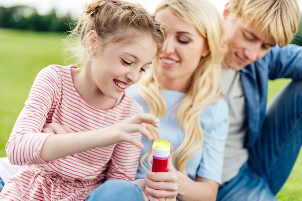 Parents with kid blowing soap bubbles — Free Stock Photo