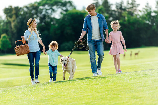 family with dog walking at park