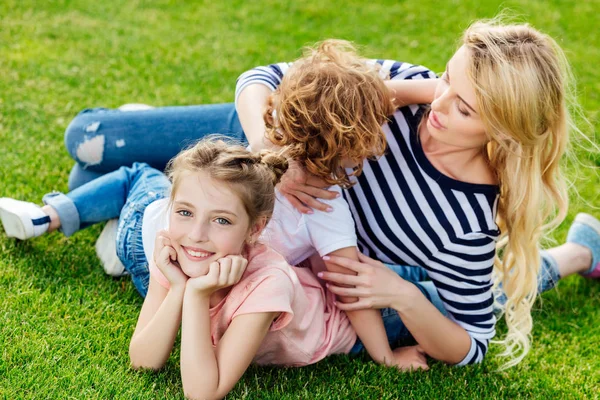 Moeder met kinderen rust op gras — Stockfoto