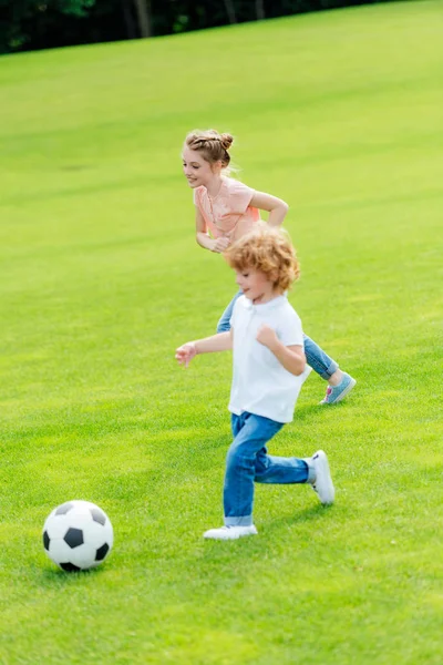 Geschwister spielen Fußball im Park — Stockfoto