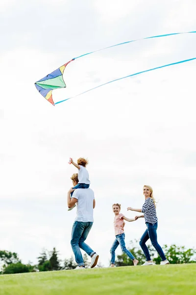 Семья играет с воздушным змеем в парке — стоковое фото