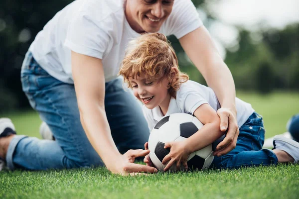 father and son playing soccer in park