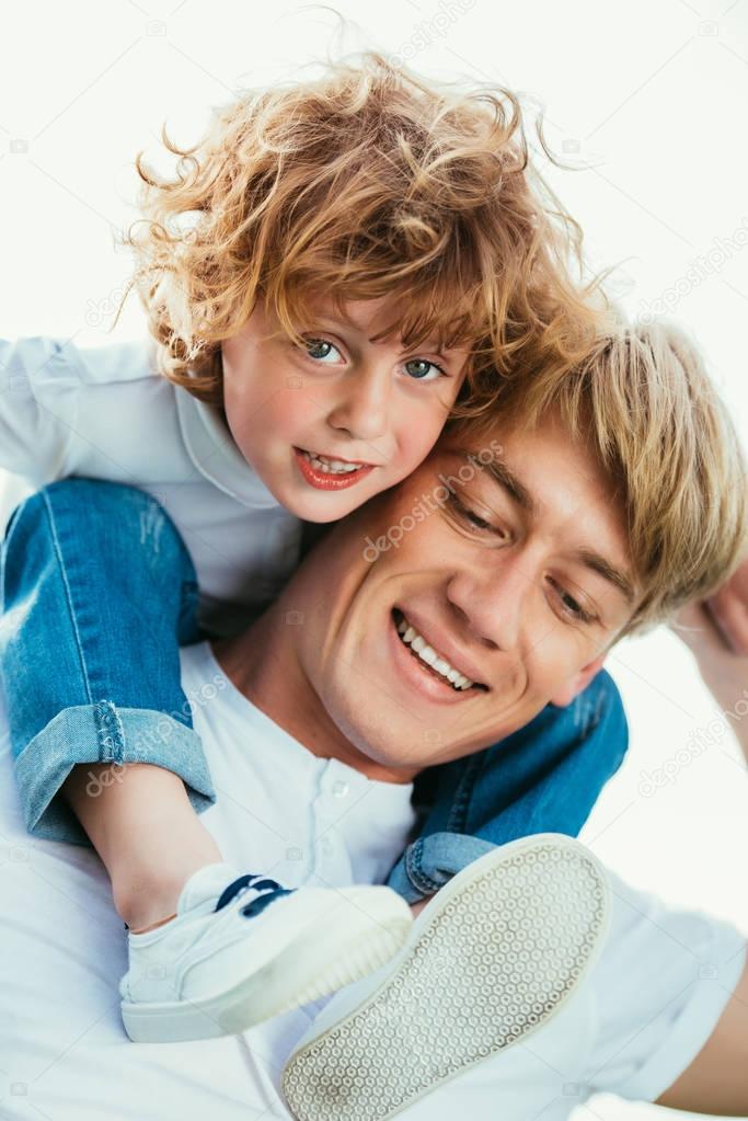 father carrying son on shoulders 