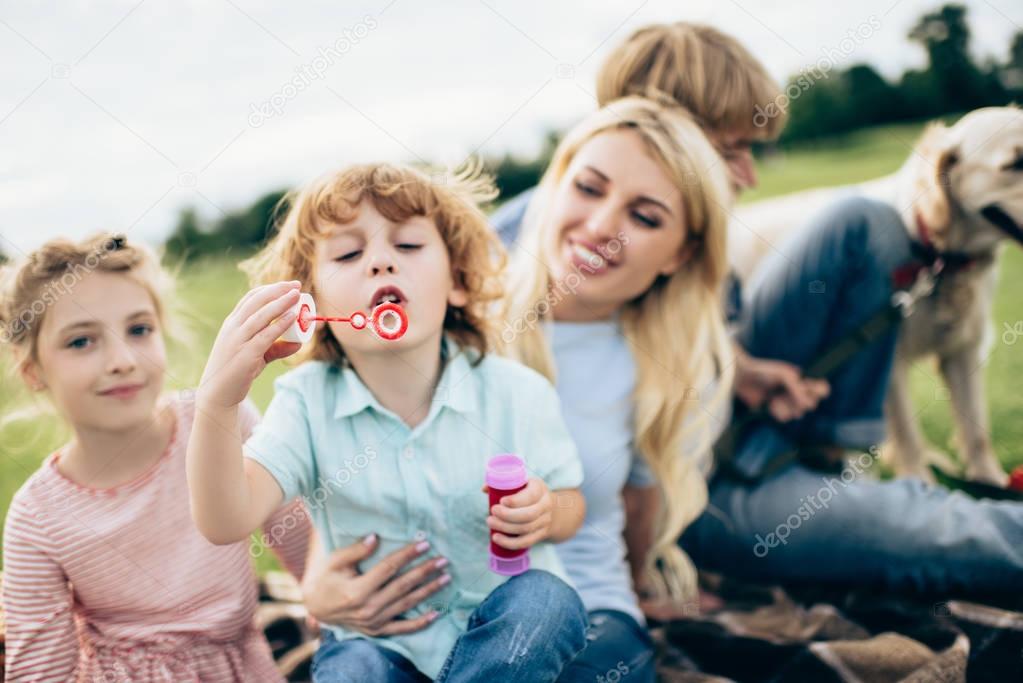 family blowing bubbles at park