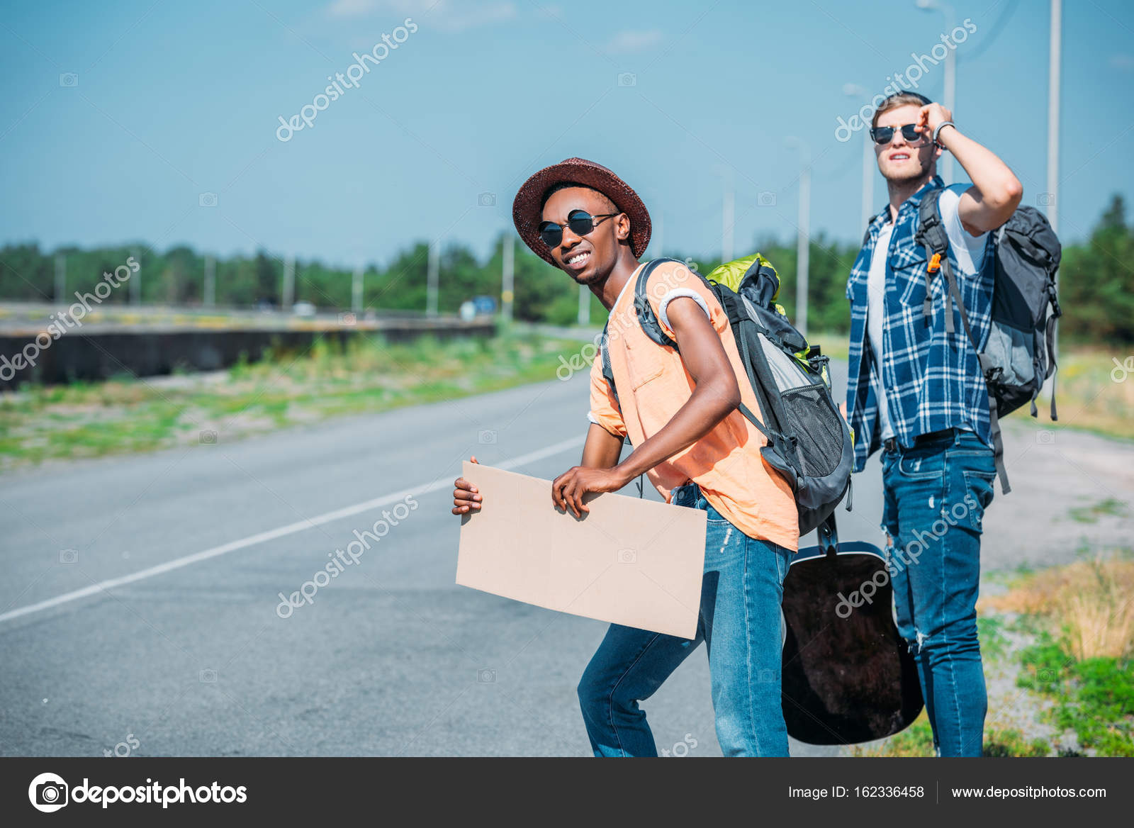 Multiethnic men with cardboard hitchhiking — Stock Photo
