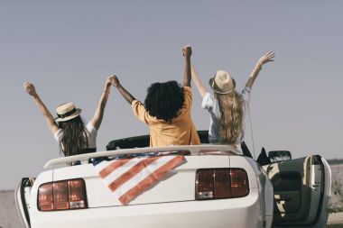 Amerikan bayrağı ile arabada oturan arkadaşlar