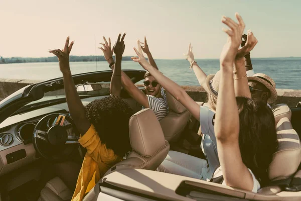 Amigos multiculturales a caballo coche en la playa — Foto de Stock