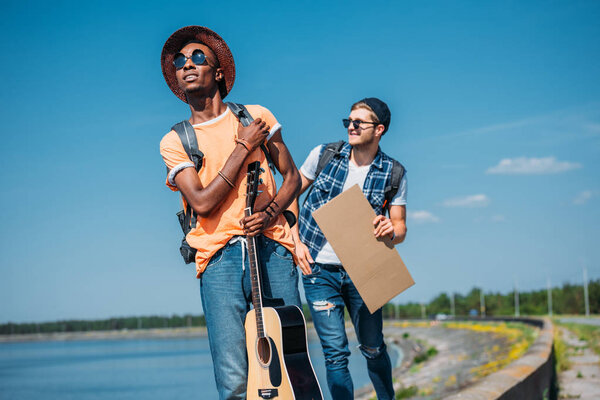 multiethnic men with empty cardboard hitchhiking 