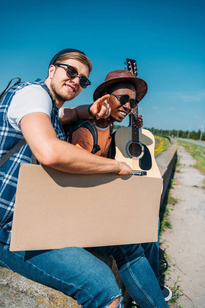 multicultural hitchhikers with cardboard