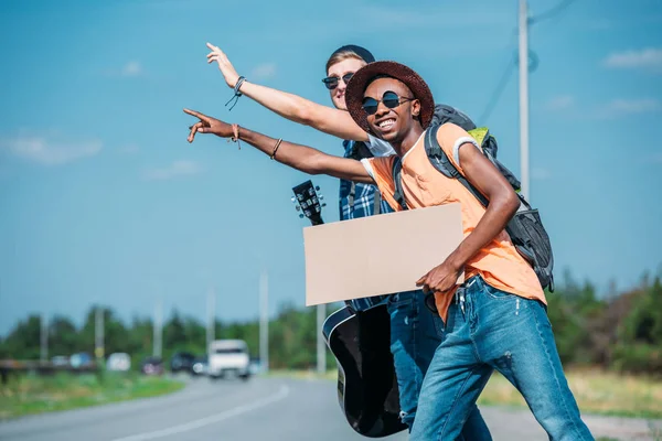 Multiethnic men with cardboard hitchhiking — Stock Photo, Image