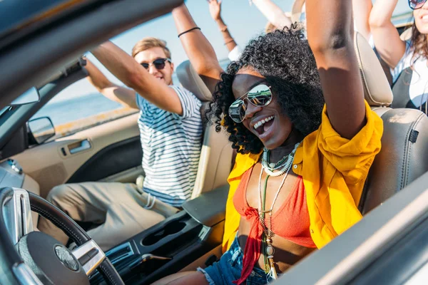 Amigos multiculturales a caballo coche en la playa — Foto de Stock