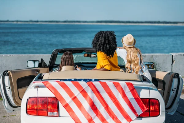 Vrienden zitten in auto met Amerikaanse vlag — Stockfoto