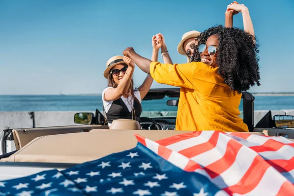 Mujeres multiétnicas en coche con bandera americana —  Fotos de Stock