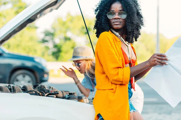 Mujeres multiétnicas de pie cerca de coche roto —  Fotos de Stock