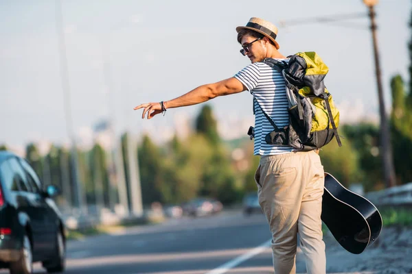 Jeune homme avec guitare auto-stop seul — Photo gratuite