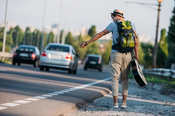 Young man with guitar hitchhiking alone — Stock Photo, Image