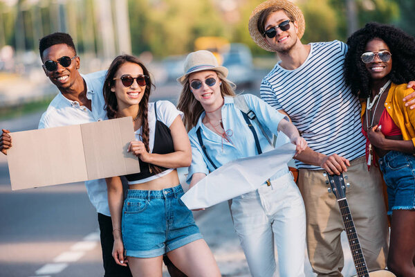 multicultural young hitchhikers with map