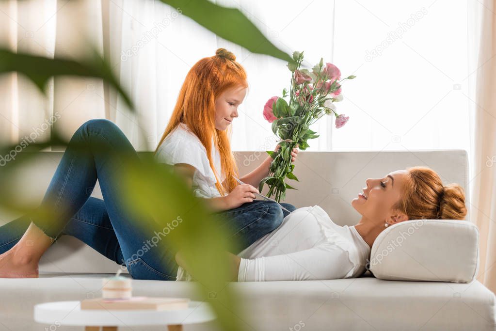 girl presenting flowers to mother