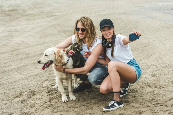 Пара с собакой делает селфи — стоковое фото
