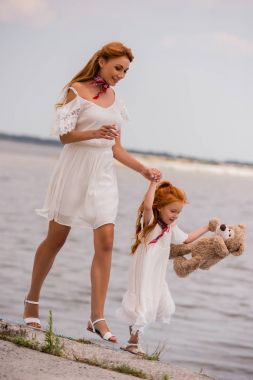 Anne ve kızı deniz kıyısı, oyuncak ayı ile