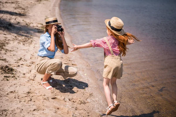 Mother photographing daughter on beach — Stock Photo, Image