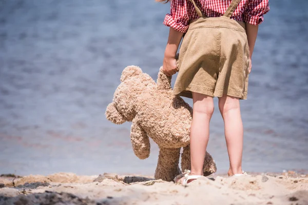 Criança com ursinho de pelúcia na praia — Fotografia de Stock