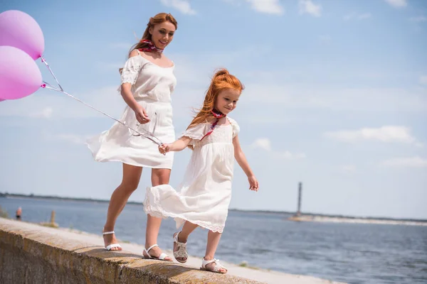 Madre e figlia con palloncini in riva al mare — Foto Stock