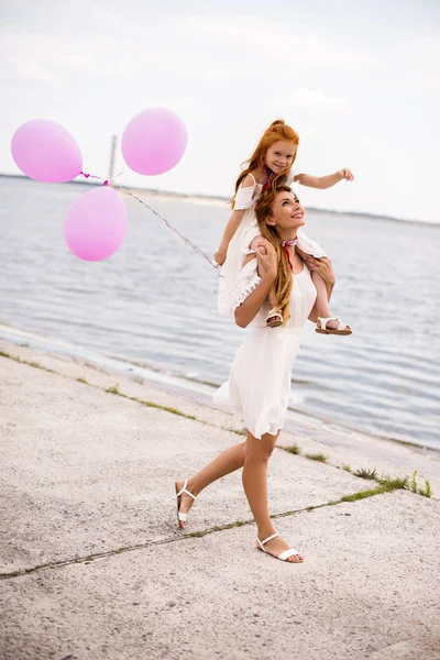 Mutter und Tochter mit Luftballons am Strand — Stockfoto