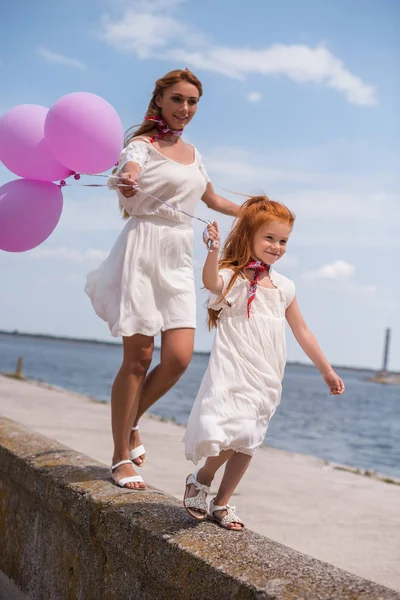 Madre e figlia con palloncini in riva al mare — Foto Stock