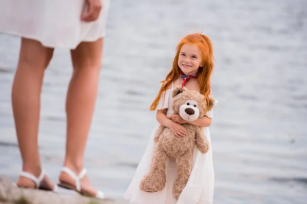 Mère et fille avec ours en peluche au bord de la mer — Photo