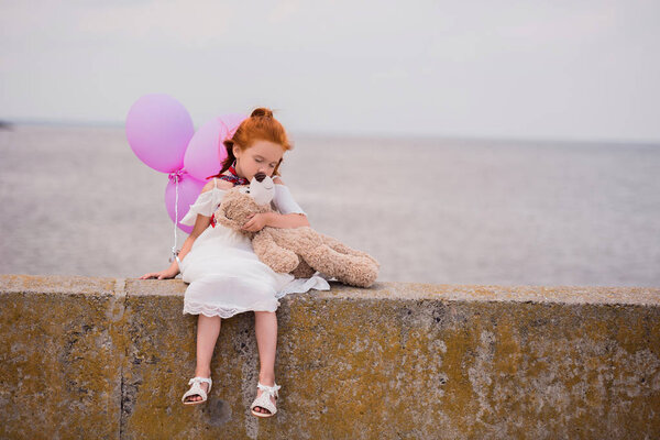 child with teddy bear and balloons