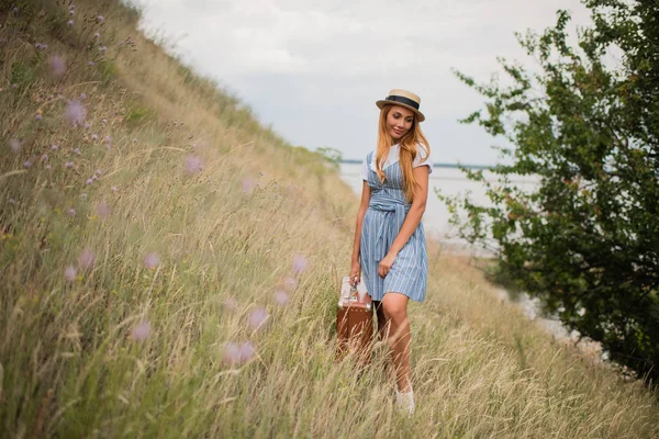 Girl with suitcase on grassland — Stock Photo, Image