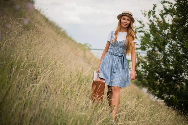 Girl with suitcase on grassland — Stock Photo, Image