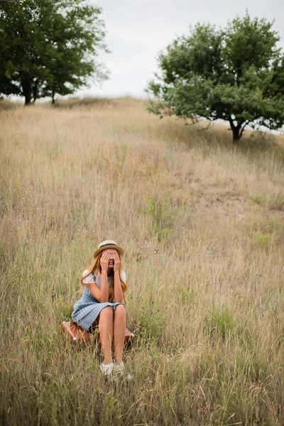 Young woman sitting on suitcase — Stock Photo, Image