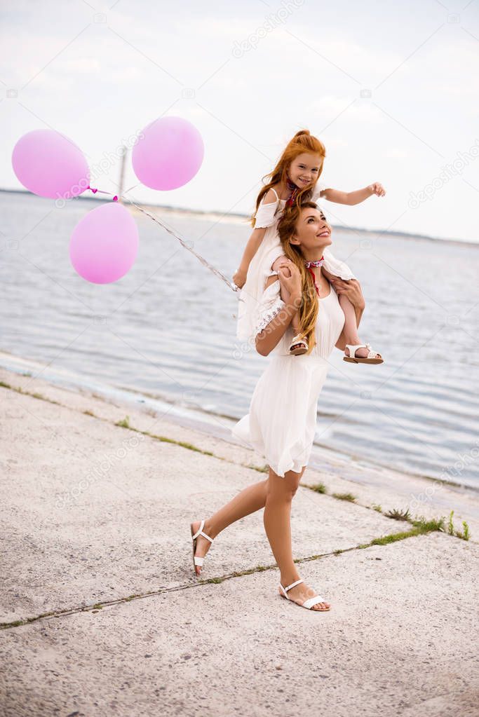 mother and daughter with balloons at seashore