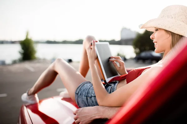 Woman using tablet on car hood — Stock Photo, Image