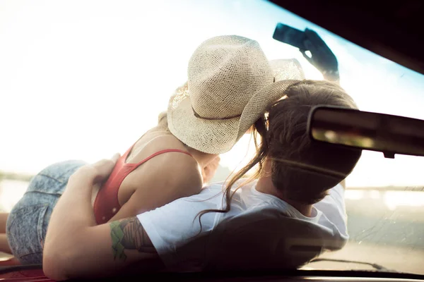 Mladý pár, ležící na auto — Stock fotografie