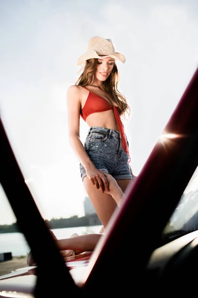 Woman standing on car hood — Stock Photo, Image