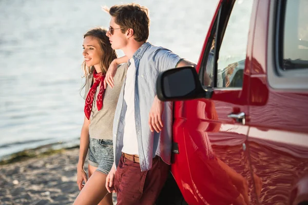 Pareja joven con coche a orillas del río — Foto de Stock