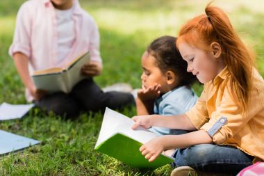 kids reading books in park clipart