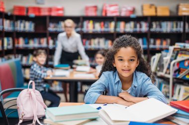 schoolgirl with pile of books at library clipart