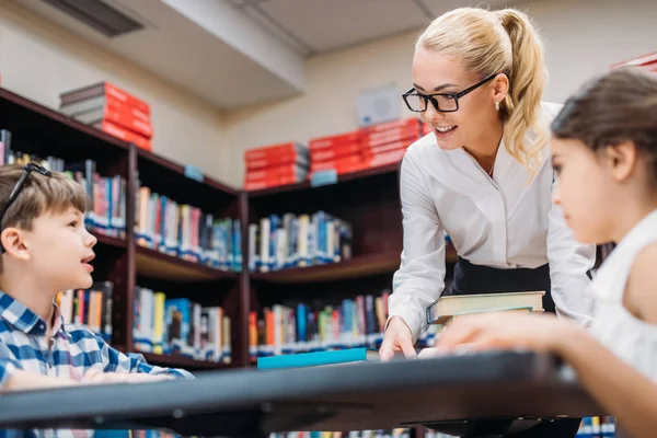 Teacher working with kids in library — Stock Photo, Image
