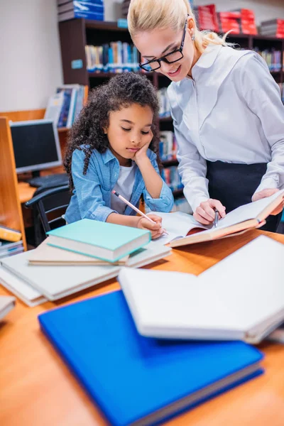 Учитель помогает школьнице с домашним заданием — стоковое фото