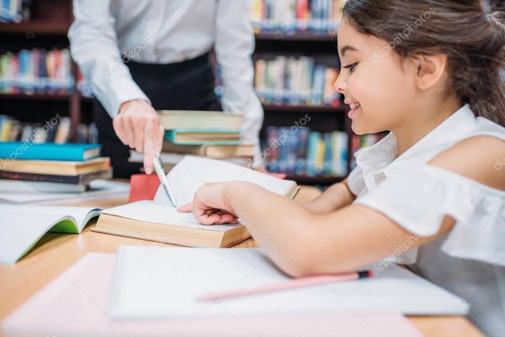 teacher helping schoolgirl with homework