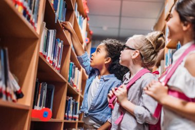 schoolgirls looking for books in library clipart