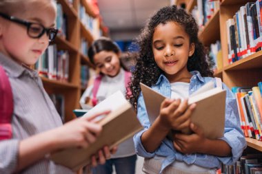 schoolgirls looking for books in library clipart